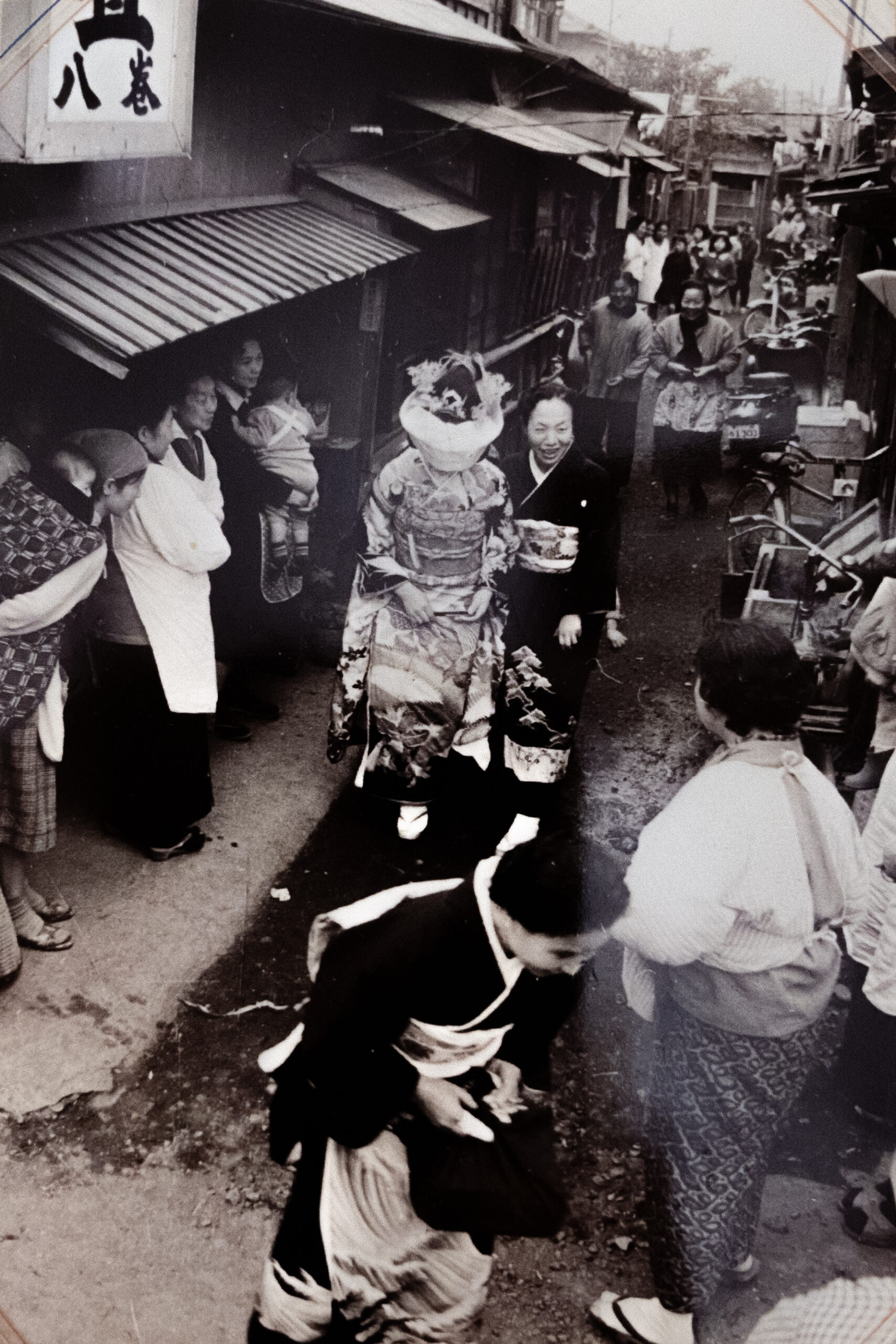 昭和30年代半ば、ばんば商店街の八巻畳工業の目の前を歩く花嫁。　<a href="https://sento-to-machi.org/kita-ku/2024/03/31/asukayamaonsen/">▶︎飛鳥山温泉とまちについて</a>